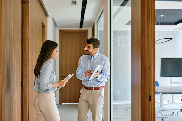 istock Business partners discussing using digital tablet and documents in office hallway 2222230832