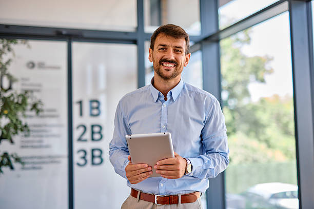 istock Businessman smiling and holding tablet in modern office 2222231086