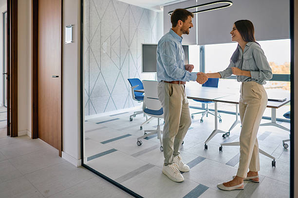 istock Two Smiling Business People Shaking Hands in Modern Office 2222231179