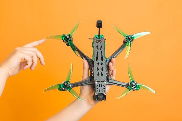 istock Professional modern drone with camera in hands isolated on orange background 2222236173