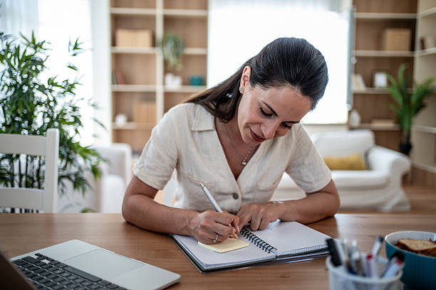 istock Focused woman writing notes in notebook at home office desk 2222238303