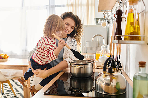 istock Curly mother and daughter bonding while cooking together at home in a bright kitchen 2222238782