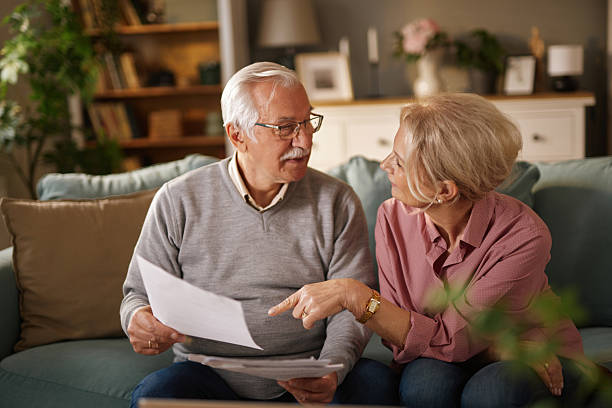 istock Senior couple reading documents and discussing life insurance at home 2222239433
