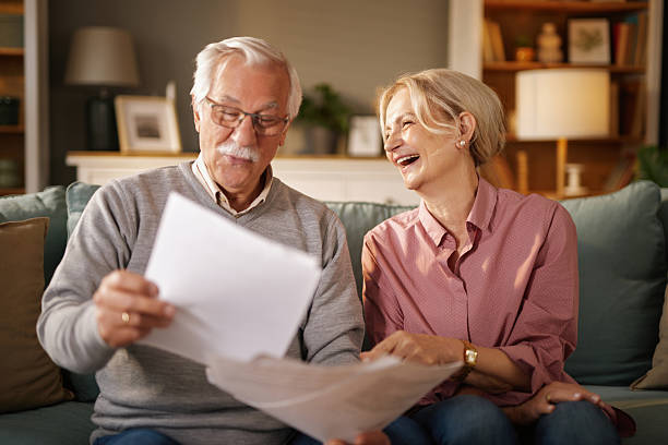 istock Happy senior couple reading documents on sofa at home, discussing life insurance 2222239528