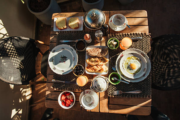 Breakfast with  bread, boiled egg, olives, cheese, fresh fruit, tea, and juice.