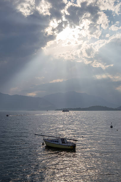istock Peaceful Lake Landscape with Boat Under Dramatic Sun Rays and Cloudy Sky 2222239969