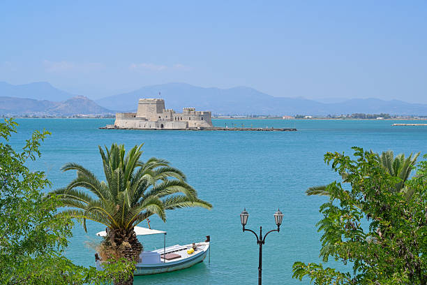 Panorama view to island Bourtzi from the harbor promenade of Nafplio (Nauplia) against blue sky. Peloponnese, Greece.