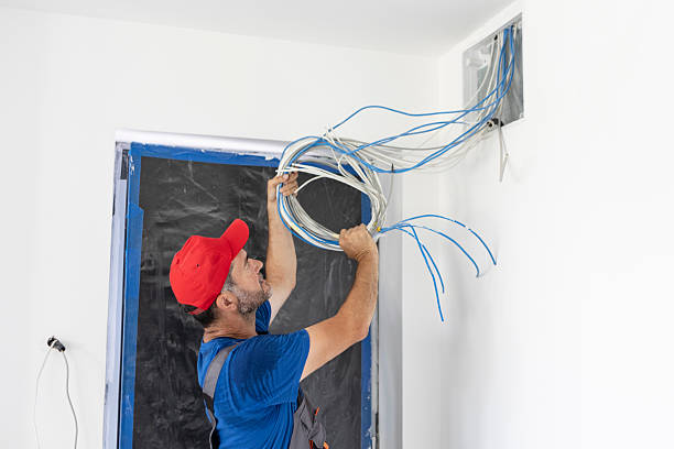 Electrician on a construction site of a new house, instaling cable TV and internet. About 45 years old, Caucasian male.