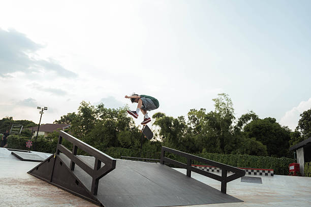 Asian male athlete doing skateboard jump during skateboard competition.