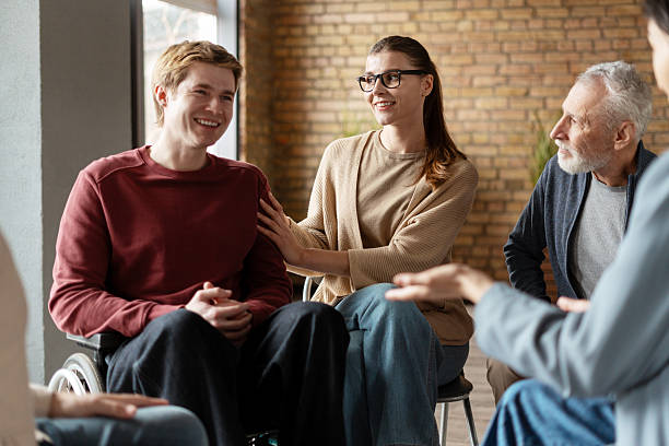 istock Therapist comforting young man in wheelchair during group therapy session 2222246129