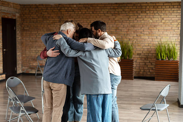 istock Diverse group of people hugging in a circle during a group therapy session 2222246153