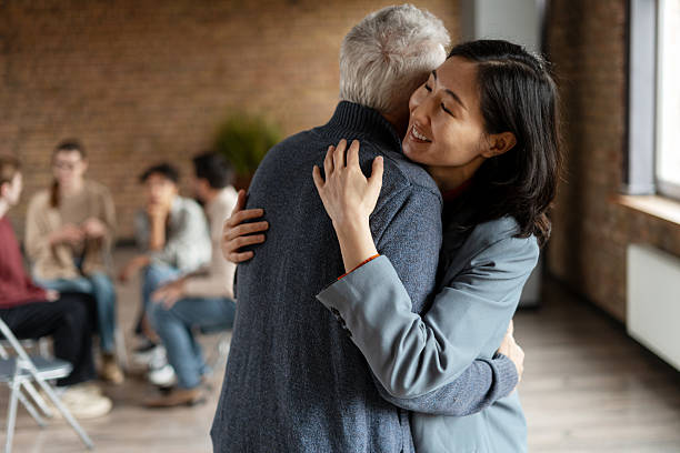 istock Daughter hugging elderly father at group therapy session 2222246168
