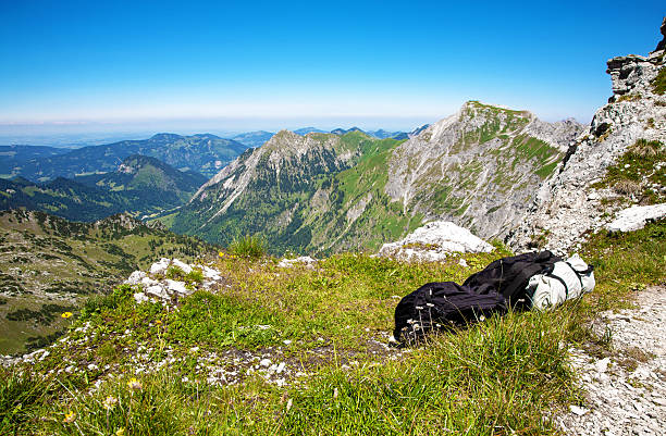 Backpack lying in the grass, Allgau Alps, Bavaria, Germany, Europe.\nBackpack in the mountain landscape of Allgau Alps, Bavaria, Germany.