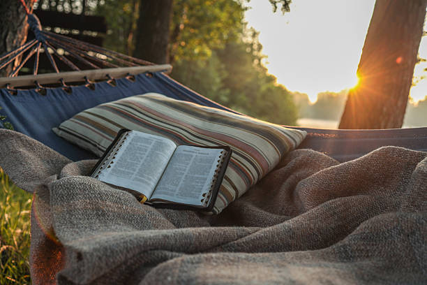 istock Open Bible resting on a striped pillow and cozy blanket in a hammock during sunrise, capturing a peaceful outdoor moment of reflection and solitude 2222251356