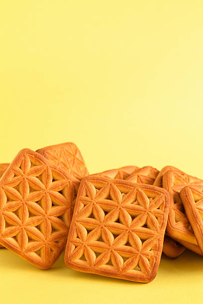 istock Sweet square shaped biscuits with floral pattern close up on a yellow background. Copy space. 2222253530