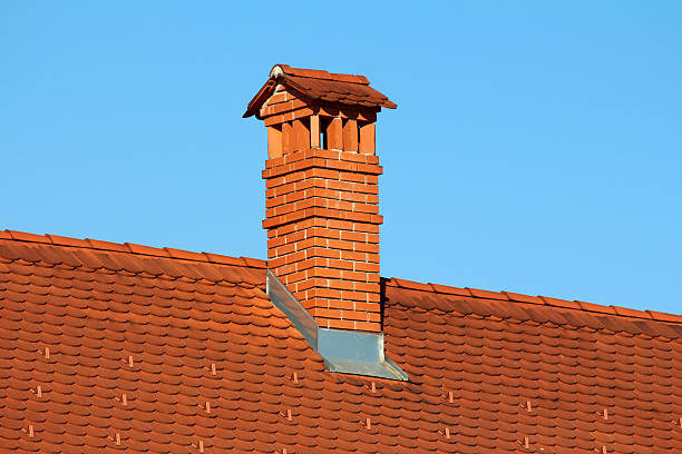 istock Red brick chimney with tile roof against clear blue sky 2222255441