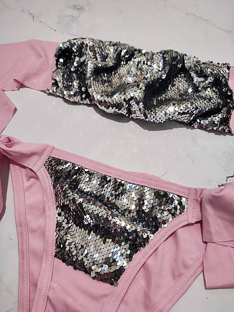 istock Pink bandeau bikini set with gray sequins flat lay close up at gray marble background. Two piece swimsuit, honeymoon women's summer beachwear, festive bikini with bows, cruise clothes, vacation 2222257585