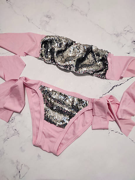 istock Pink bandeau bikini set with gray sequins flat lay close up at gray marble background. Two piece swimsuit, honeymoon women's summer beachwear, festive bikini with bows, cruise clothes, vacation 2222257586