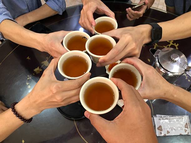 High angle view of adult hands holding tea cups toasting tea