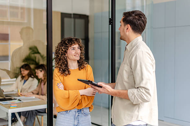 istock Engaging conversation between colleagues in a modern office setting with young professionals working 2222262457