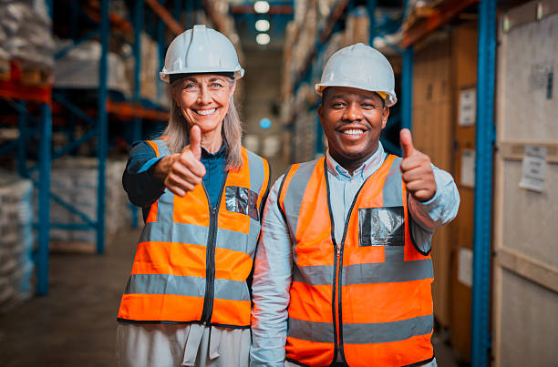 istock Warehouse Workers Giving Thumbs Up, Displaying Safety Vests and Helmets in Logistics Facility 2222265235