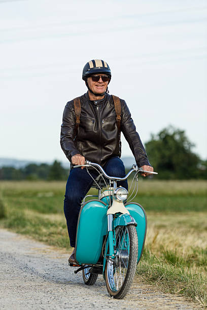 istock Smiling Senior Man on an Old Moped Riding on Rural Road 2222268205