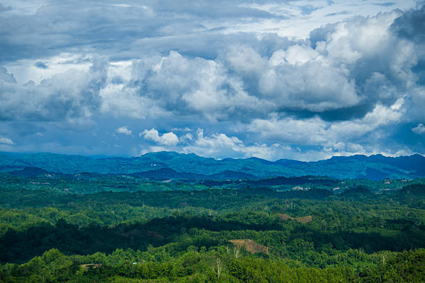 Landscape of Green hills where cloud floating in sky line and and make shadow. And this shadow make dark spots on the green hills.