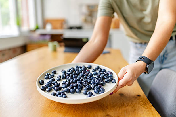istock Woman enjoying fresh blueberries while promoting healthy eating in a bright kitchen setting 2222271635