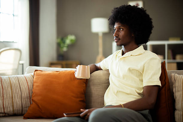 istock Young man relaxing on sofa, drinking coffee and watching tv 2222272134