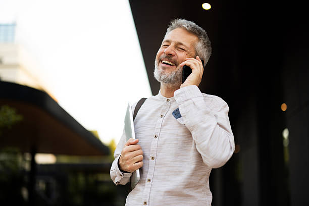 istock Mature businessman laughing while talking on phone and holding tablet 2222272915