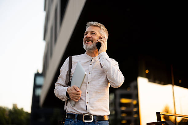 istock Smiling businessman walking and talking on smartphone in urban setting 2222272936