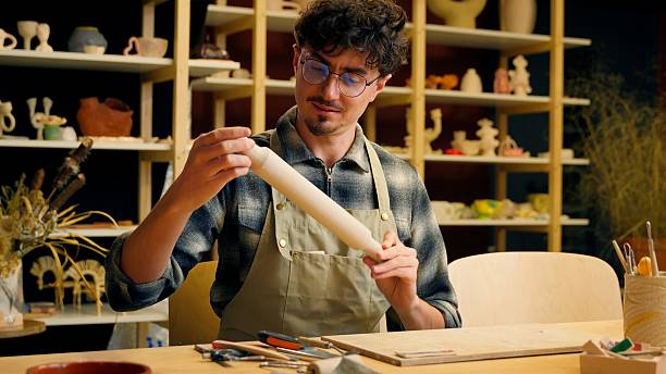 istock Craftsman guy man potter sculptor holding rolling pin pottery instrument clay modeling tool Caucasian male artisan small business owner ceramics shop handmade sculpting craft hobby ceramics on table 2222275690