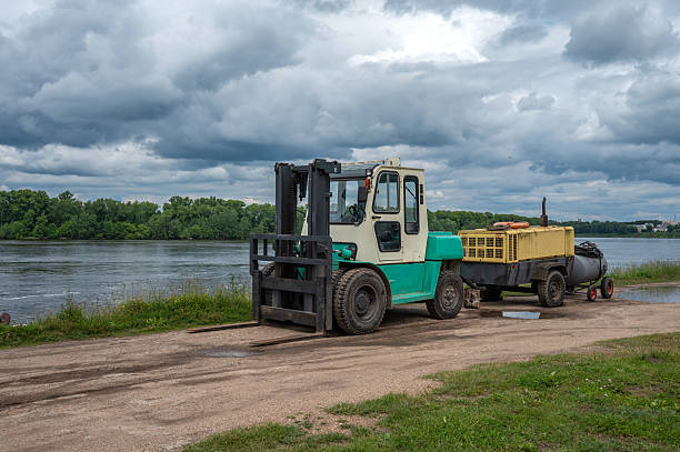 A forklift with a compressor on a trailer on the river bank.