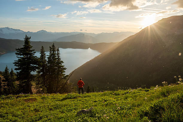 istock Man watches sunrise over mountains, forest and lake, B.C. 2222285676