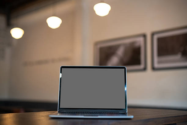 Mockup of laptop computer with empty screen on table side the window in the coffee shop at the cafe,grey screen