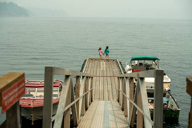 Young girls stand on boat pier over ocean, British Columbia