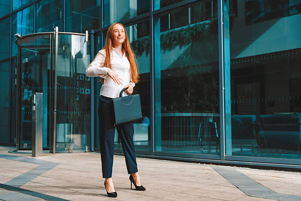 istock Business professional walking confidently outside a modern office building on a sunny day while holding a handbag 2222291175