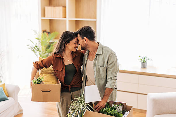 istock Happy couple moving into new home carrying boxes and showing affection 2222291373