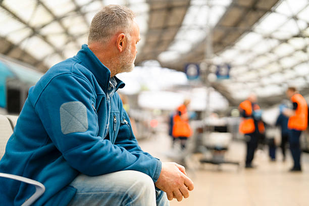 istock Man waiting in a busy train station during daytime, observing staff in bright uniforms assisting passengers nearby 2222292081