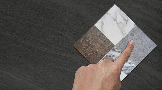 istock interior architect's hand picks tile samples in white, grey and brown  collection on dark black marble stone background with blank space for design. 2222292176