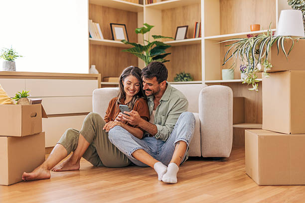 istock Happy couple using smartphone while taking a break from moving into new home 2222292306