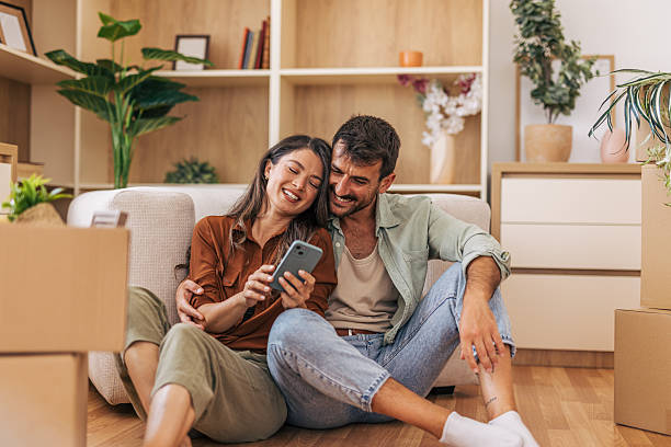 istock Happy couple using smartphone while taking a break from moving into new home 2222292339