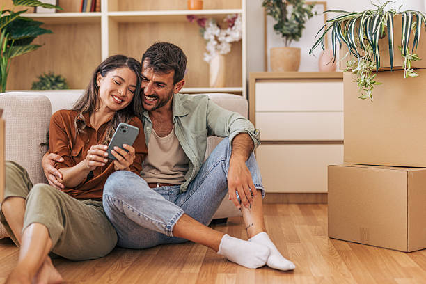 istock Happy couple using smartphone while taking a break from moving into new home 2222292343