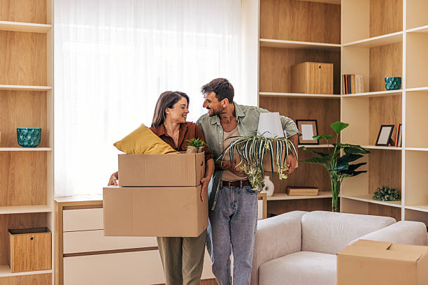 istock Happy couple carrying boxes and plants into new home 2222293048