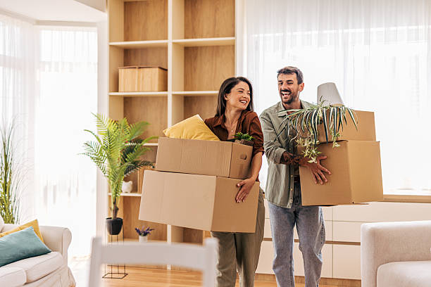 istock Happy couple carrying boxes and plants into new home 2222293739
