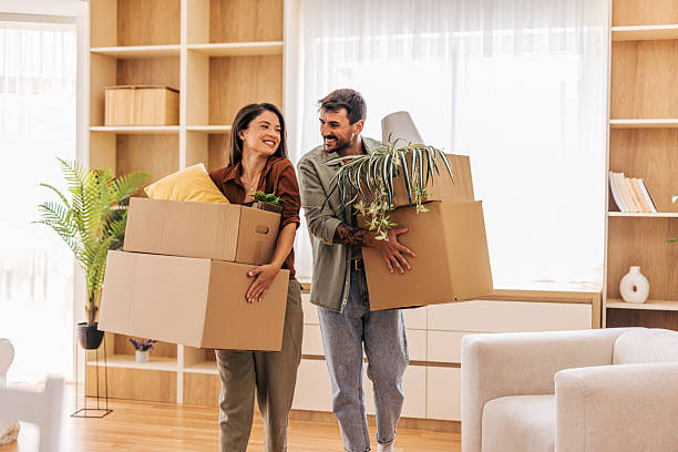 istock Happy couple carrying boxes and plants into new home 2222293741