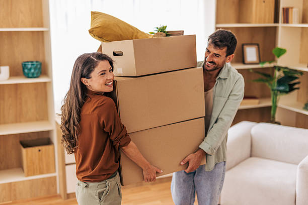 istock Happy couple carrying stacked boxes into new home 2222293998