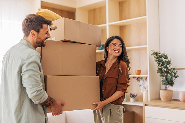 istock Happy couple carrying stacked boxes while moving into new home 2222294349