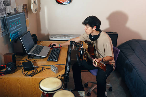 istock Young musician composing music with guitar and computer in home studio 2222294427