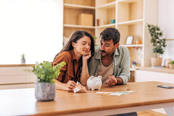 istock Young couple saving money at home using piggy bank 2222294584